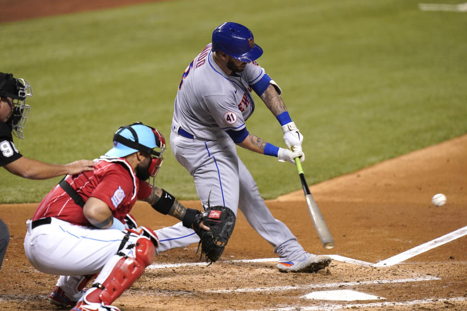 New York Mets' Tomas Nido hits a double to score Dominic Smith during the fourth inning of a baseball game against the Miami Marlins, Friday, May 21, 2021, in Miami. At left is Marlins catcher Sandy Leon. (AP Photo/Lynne Sladky)