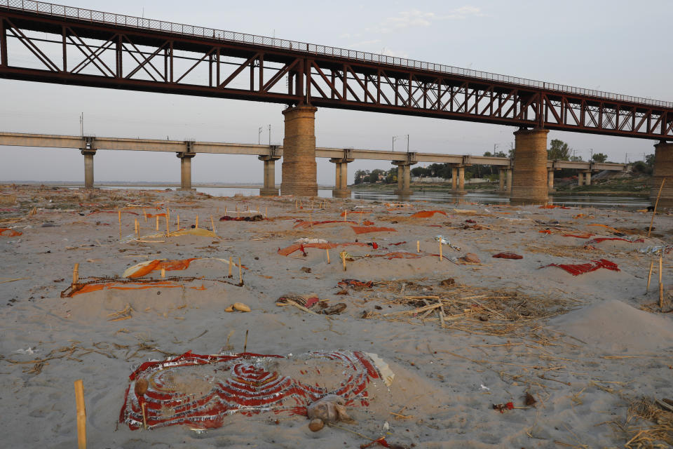 Bodies are seen under colourful cloth on the banks of Ganges River. 