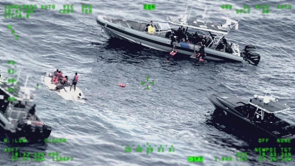 This photo released by the Seventh U.S. Coast Guard District shows people standing on a capsized boat, left, on May 12, 2022 as some of its passengers are pulled up on to a rescue boat, top, in the open waters northwest of Puerto Rico. (Seventh U.S. Coast Guard District via AP, File)