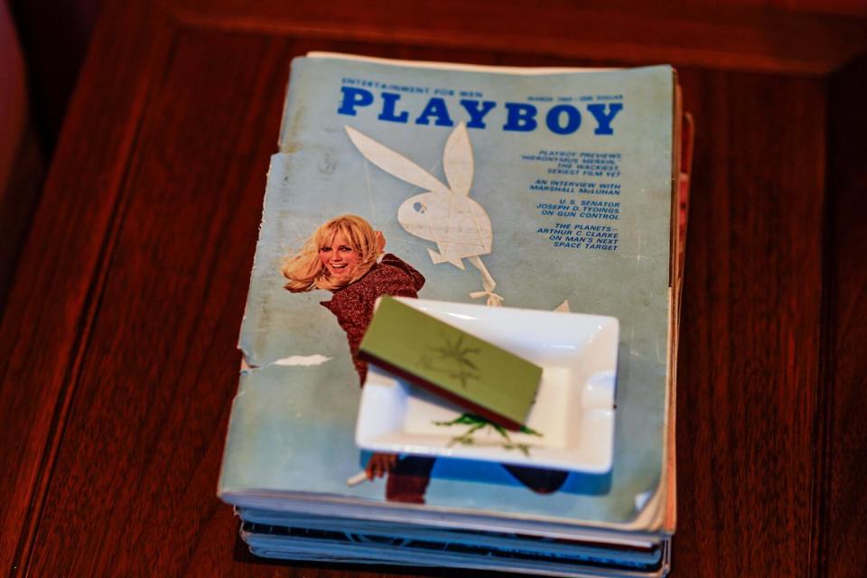 An ashtray and a matchbox atop a stack of Playboy magazines