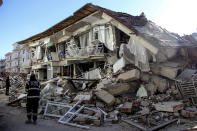 Rescue workers try to reach people under a collapsed building following a strong earthquake in Elazig in the eastern Turkey, Saturday, Jan. 25, 2020. The earthquake rocked eastern Turkey on Friday, causing some buildings to collapse and killing scores of people, Turkish officials said. (IHA via AP)