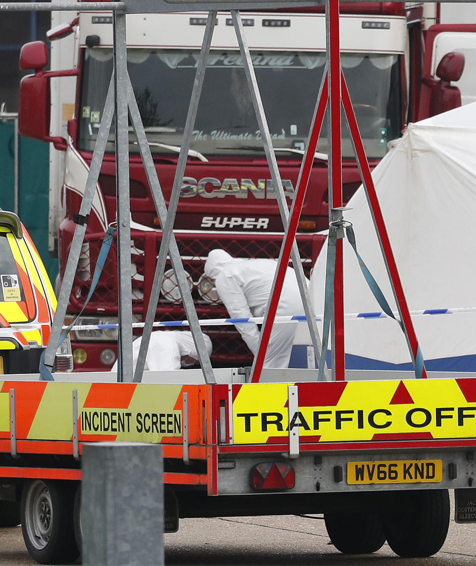 Police forensic officers attend the scene after a truck, in rear, was found to contain a large number of dead bodies, in Thurrock, South England, early Wednesday Oct. 23, 2019. Police in southeastern England said that 39 people were found dead Wednesday inside a truck container believed to have come from Bulgaria. (AP Photo/Alastair Grant)