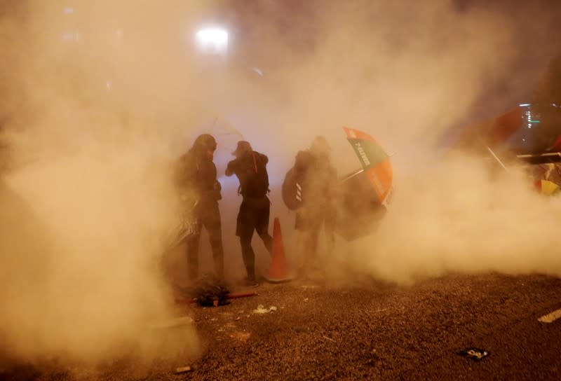 Anti-government demonstrators stand amid tear gas during clashes with police near the Hong Kong Polytechnic University (PolyU) in Hong Kong