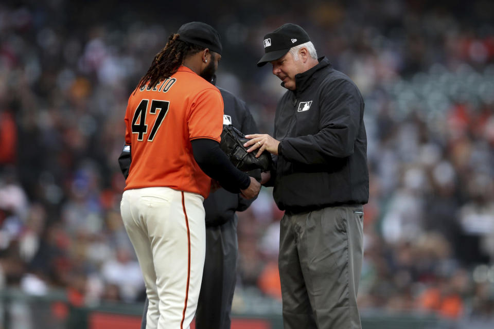 San Francisco Giants' Johnny Cueto, left, has his equipment checked for foreign substances by umpire Tim Timmons against the Oakland Athletics during the first inning of a baseball game in San Francisco, Friday, June 25, 2021. (AP Photo/Jed Jacobsohn)