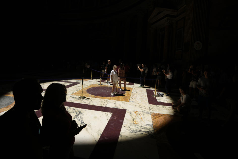 Tourists visiting the interior of Rome's Pantheon stand in the light circle projected on the marble floor by the dome's central opening (oculus), Friday, June 17, 2022. Summer travel is underway across the globe, but a full recovery from two years of coronavirus could last as long as the pandemic itself. In Italy, tourists — especially from the U.S. — returned this year in droves. (AP Photo/Alessandra Tarantino)
