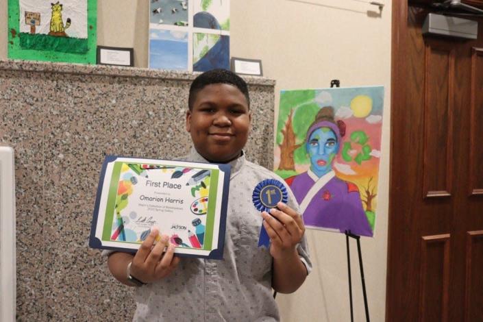 First place winner Omarion Harris of Northeast Middle School stands with his winning artwork in City Hall.