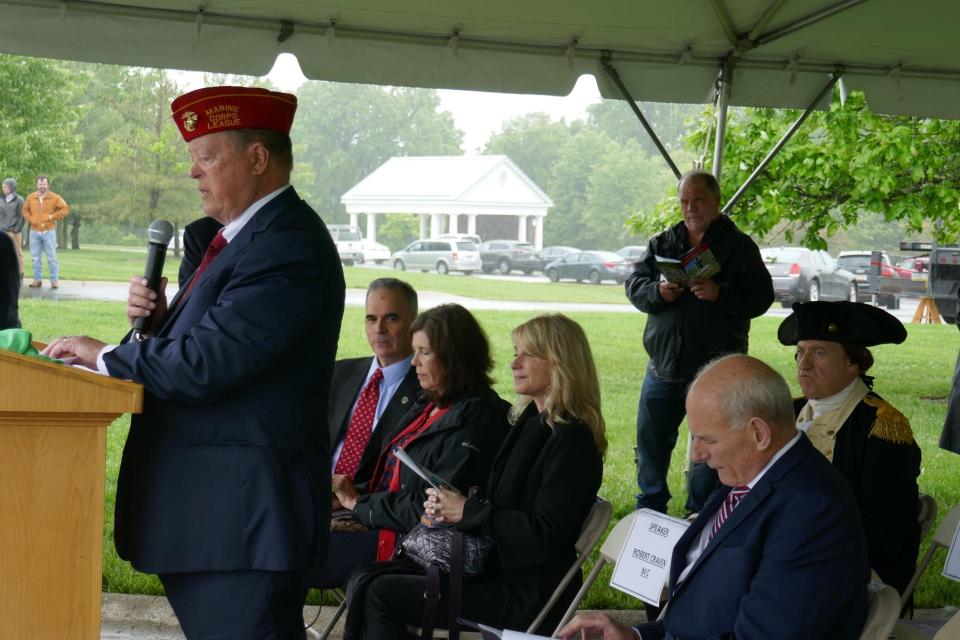 John Heenan, chairman of the  Washington Crossing Guardians Monument Committee, introduces Gen. John Kelly (seated at right) to the unveiling of the statue of George Washington at Washington Crossing National Cemetery.  George Washington re-enactor John Godzieba is seated behind him.