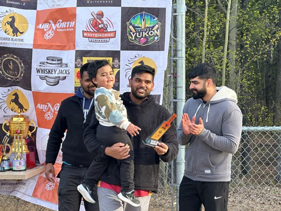 Stephen Masih accepts the award for best batsman with his son in his arms at the Yukon Cricket Association 2024 tournament in Whitehorse. 