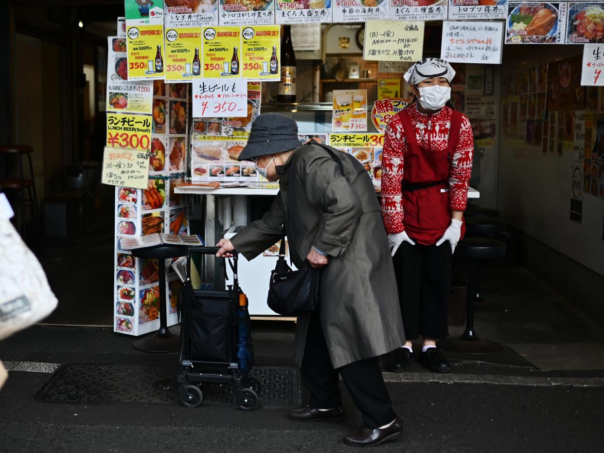 An elderly woman crosses the street in Japan.