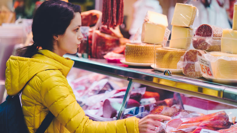 woman points into deli case