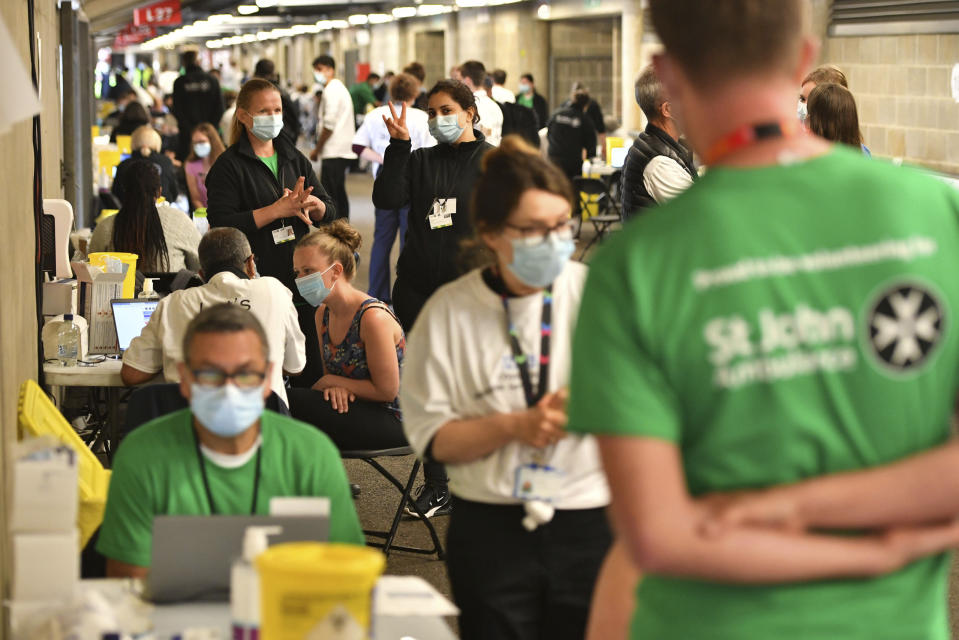 People queue up to receive a coronavirus vaccination at a surge vaccine operation set up at Twickenham rugby stadium, south-west London, Monday May 31, 2021. Up to 15,000 doses of vaccine are ready to be administered at the walk-in centre which has been set up for residents of north-west London in response to an increase in the number of coronavirus cases in the area. (Dominic Lipinski/PA via AP)