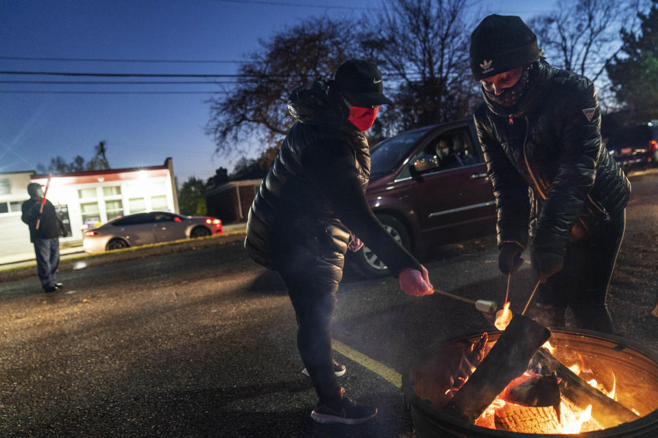Volunteers Latrina Lawrence, left, and Breya Smith, roast marshmallows for motorists pulling through a drive-thru socially distanced Halloween celebration in the parking lot of The Winner's Circle Church in Mount Clemens, Mich., Saturday, Oct. 31, 2020. According to pastor Leon McDonald III, the event was intended to bring a sense of normalcy to its congregation amid coronavirus lockdowns and a sense of anxiety leading up to the election. (AP Photo/David Goldman)