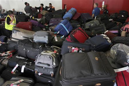 Airport officials sort a large pile of luggage inside Terminal 3 outside the area where a shooting incident occurred the previous day at Los Angeles airport (LAX), California November 2, 2013. REUTERS/David McNew