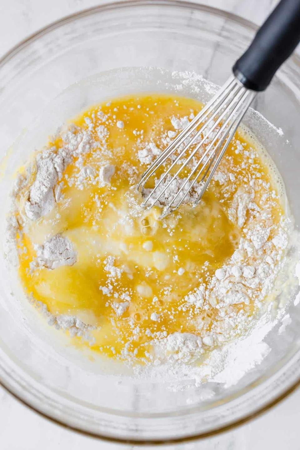 Mixing bowl with whisk and ingredients partially combined, likely for baking