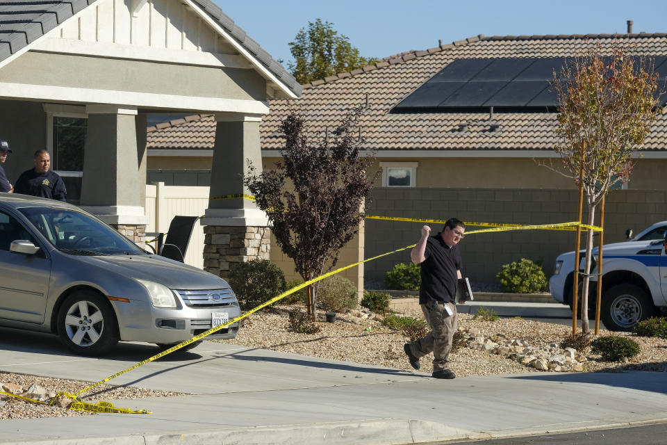 A law enforcement leaves a home where five bodies were found in the city of Lancaster in the high desert Antelope Valley north of Los Angeles, Monday, Nov. 29, 2021. A Los Angeles County Sheriff's Department statement says deputies found a woman, a girl and three boys with gunshot wounds and paramedics pronounced them dead at the scene. The department says the children's father showed up at the Lancaster sheriff's station and was arrested on suspicion of five murders after being interviewed by detectives. (AP Photo/Ringo H.W. Chiu)