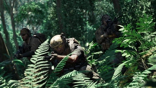  An armed  soldier crouches in the Southeast Asian jungle. 