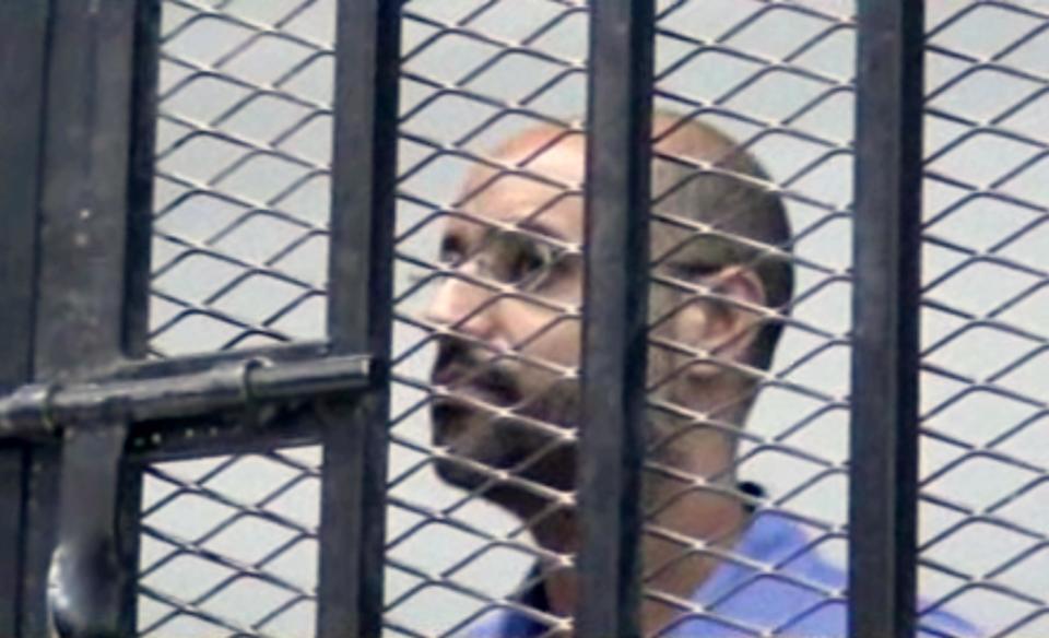 FILE - This image Thursday, Sept. 19, 2013 file photo made from AP video shows Seif al-Islam Gadhafi, son of Libya's former dictator Moammar Gadhafi, inside a cage in a courtroom in Zintan, Libya. A Libyan judge in the trial of former regime officials has decided that Moammar Gadhafi's son, held by a militia in the country's west, can attend the proceedings through a video link. Since the end of Libya's 2011 civil war, Seif al-Islam Gadhafi has been held by a militia in Zintan, which has refused to hand him over for a separate trial in the capital, Tripoli — a sign of the central government's weakness. Al-Islam faces charges along with 39 other Gadhafi regime figures — including notorious spymaster Abdullah al-Senoussi — for alleged crimes during Libya's conflict.(AP Photo via AP video, File)