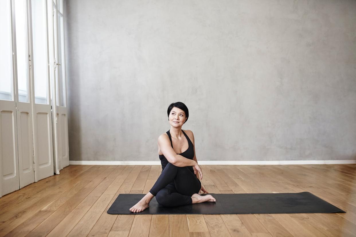 woman in studio room stretching on a yoga mat