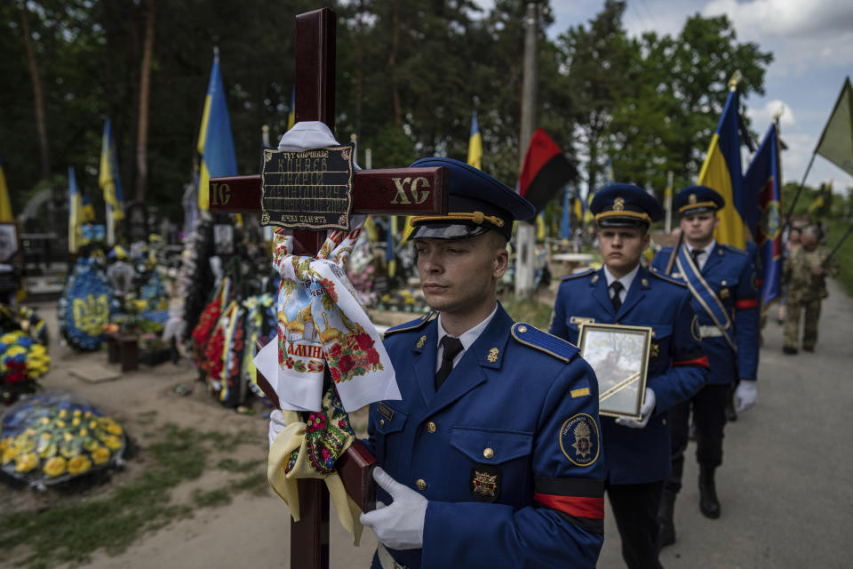 Soldiers carry a cross and photo of their comrade Andrii Konyaev, a member of the Azov regiment defending Mariupol, who was killed on July 29, 2022, at Olenivka, a Russian war prisoner camp, during a funeral ceremony in Fastiv, Ukraine, Tuesday, May 23, 2023. (AP Photo/Evgeniy Maloletka)