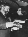 <p>French cartoonist Raymond Peynet talks to Sophia Loren over a copy of her book, <em>Cooking...with Love</em>, which he illustrated for her, aboard the boat Raffaelo, moored in Cannes, France in 1971.</p>