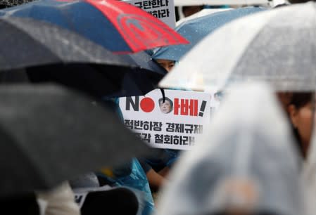 A woman holds a banner that reads "No Abe! withdraw economic sanction!" during an anti-Japan protest on Liberation Day in Seoul