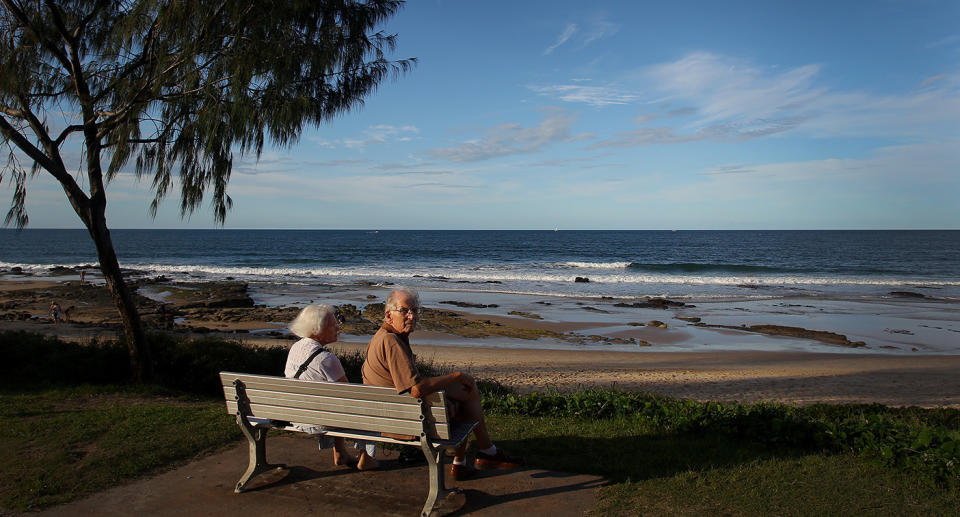 An elderly couple sit and look out across Mooloolaba main beach in Mooloolaba, Australia. 