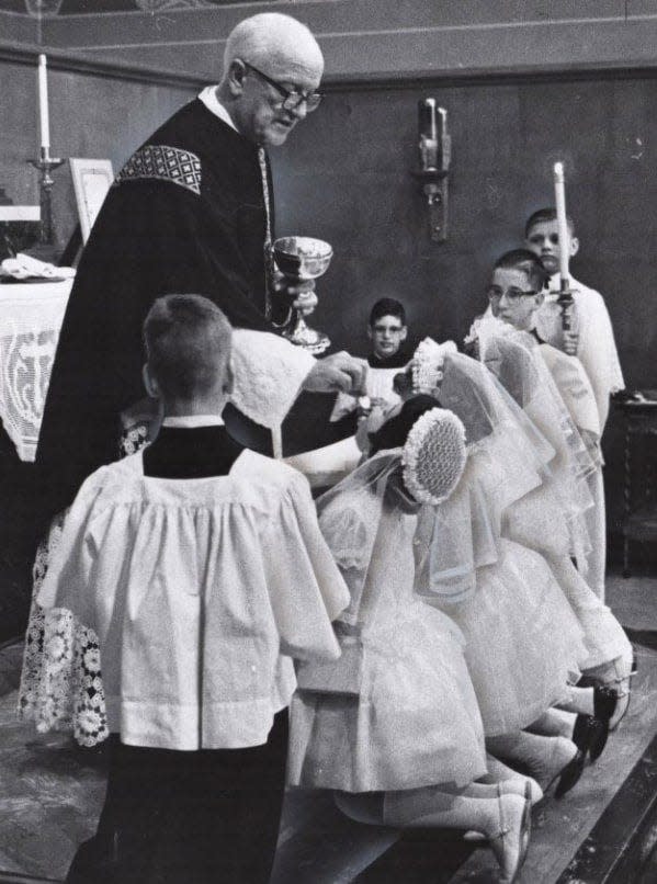 The Rev. Frederick Hitch, pastor of Immaculate Conception Church in Kenmore, administers a second communion in memory of President John F. Kennedy in 1963.
