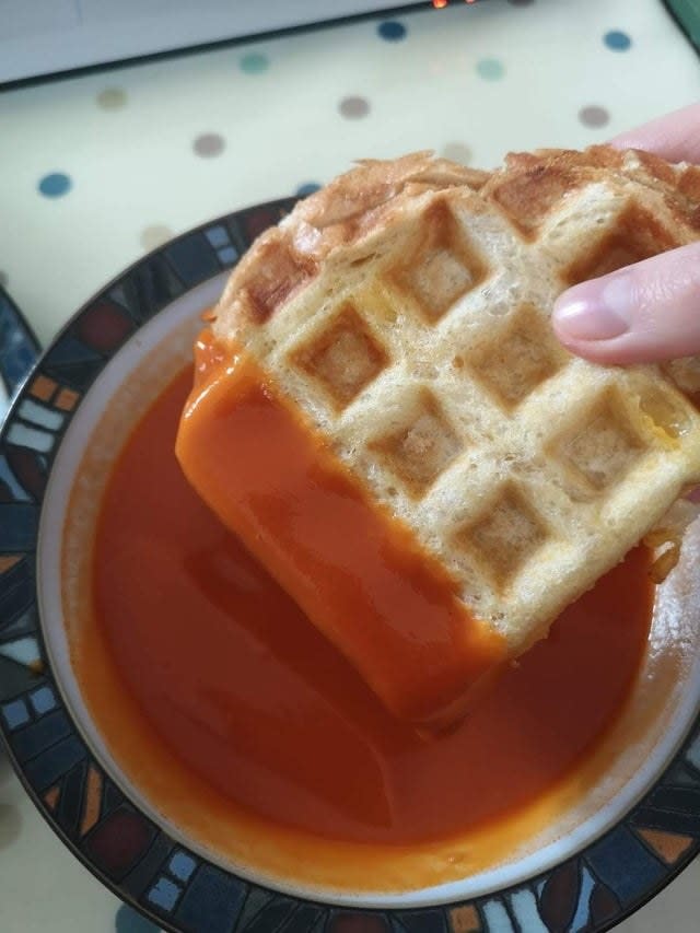 A waffle iron grilled cheese dipped in tomato soup.