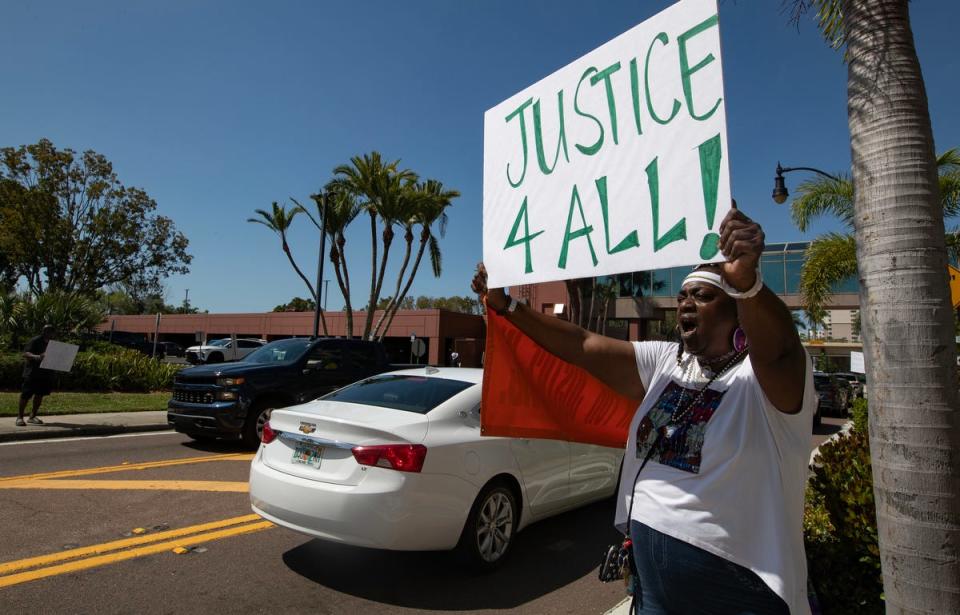 Fort Myers resident Tracy Howards holds a signs while protesting in downtown Fort Myers Friday afternoon, March 15, 2024. Members of the Lee County NAACP held a rally in front of the office of the state attorney to protest the handling of the Fort Myers Police Department fatal shooting of Christopher Jordan on December 1, 2023.