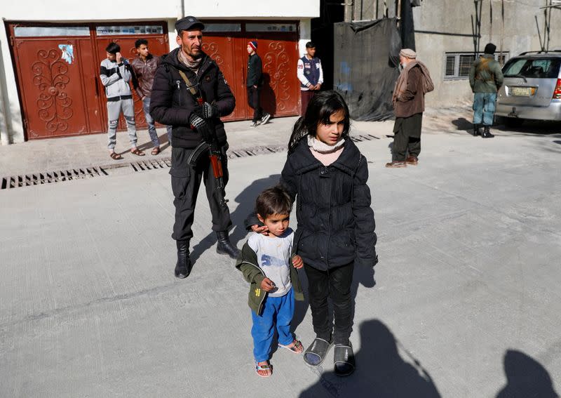 Children watch as body of female judge shot dead by gunmen is carried by relatives in Kabul