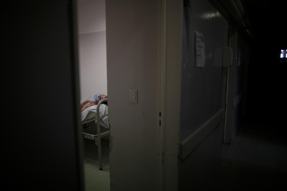 A patient with COVID-19 symptoms lies on a bed at the Eurnekian Ezeiza Hospital in Buenos Aires, Argentina, Thursday, Aug. 13, 2020. At a time when the number of deaths due to COVID-19 has increased in Argentina, several hospitals are implementing protocols on their own initiative that allow people to say goodbye to their loved ones in person. Among politicians there is also a greater interest in humanizing this process and a project presented in the capital's legislature proposes to regulate "the right to say goodbye". (AP Photo/Natacha Pisarenko)