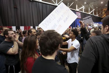 Trump supporters cheer as an anti-Trump protester (C) is escorted out of the arena during a campaign rally for Republican U.S. presidential candidate Donald Trump in Cleveland, Ohio, March 12, 2016. REUTERS/Rebecca Cook