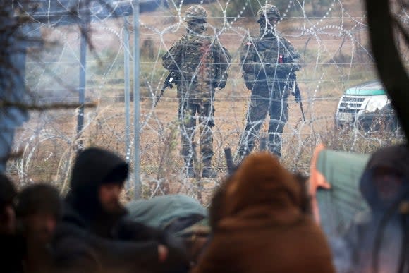 Polish border guards stand near the barbed wire as migrants from the Middle East and elsewhere gather at the Belarus-Poland border