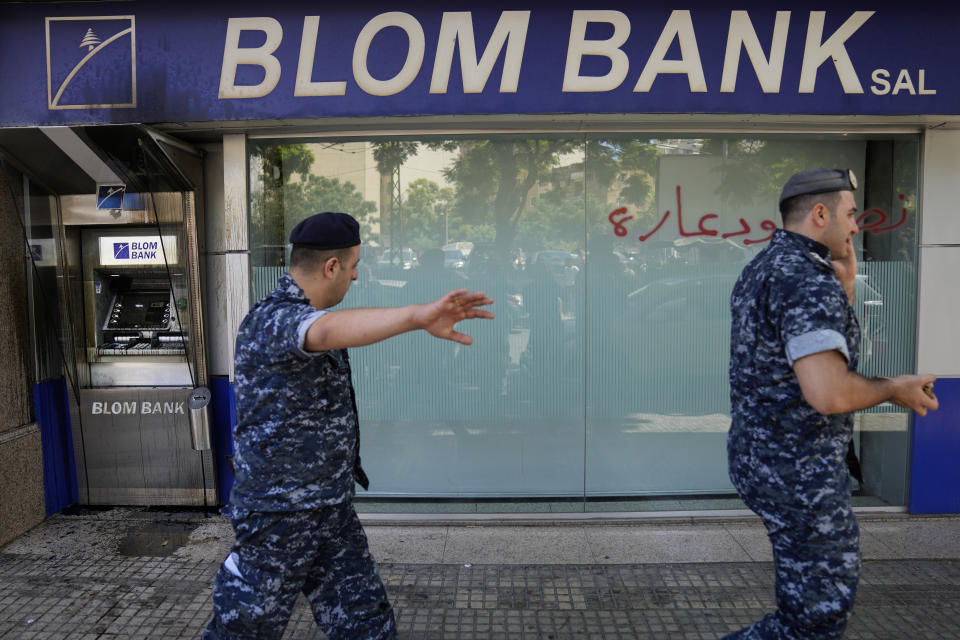 Lebanese policemen pass next to a bank that was attacked by depositors, in Beirut, Lebanon, Wednesday, Sept. 14, 2022. An armed woman and a dozen activists broke into a Beirut bank branch on Wednesday, taking over $13,000 from what she says were from her trapped savings. Lebanon's cash-strapped banks since 2019 have imposed strict limits on withdrawals of foreign currency, tying up the savings of millions of people. (AP Photo/Hussein Malla)