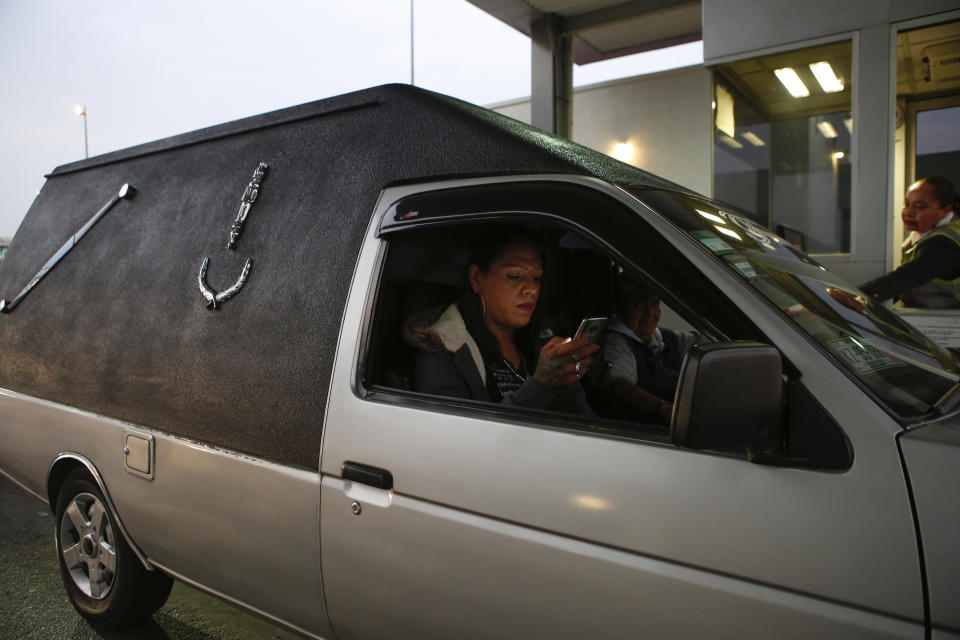In this Aug. 16, 2019 photo, trans rights activist Kenya Cuevas checks her cellphone as she rides with her friend Concepción Herrera, who is a funeral service worker, in Chalco, Mexico. In the annual Pride parade this June, Cuevas road on top of the hearse to call attention to the violence her community continues to suffer. (AP Photo/Ginnette Riquelme)