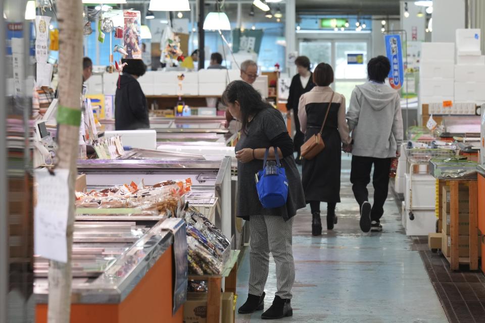 Visitors check seafood sold at the seafood market "Lalamew" near the Onahama fish port in Iwaki City, Fukushima Prefecture, on Oct. 19, 2023 in Iwaki, northeastern Japan. Fishing communities in Fukushima feared devastating damage to their businesses from the tsunami-wrecked nuclear power plant’s ongoing discharge of treated radioactive wastewater into the sea. Instead, they're seeing increased consumer support as people eat more fish, a movement in part helped by China’s ban on Japanese seafood. (AP Photo/Eugene Hoshiko)