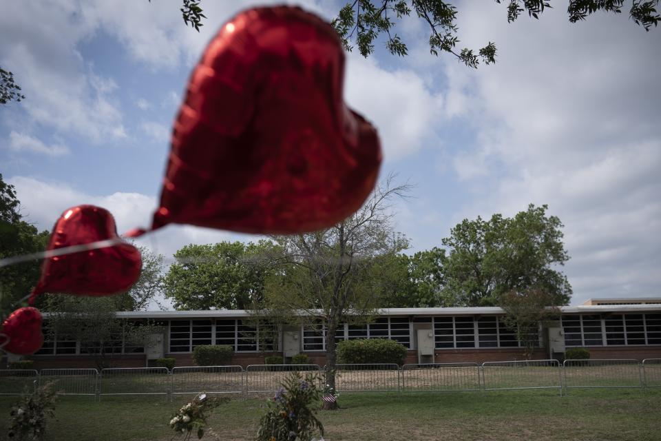 A heart-shaped balloon flies decorating a memorial site outside Robb Elementary School in Uvalde, Texas, Monday, May 30, 2022. Nineteen children and two teachers were killed by an 18-year-old gunman at the school last week. (AP Photo/Wong Maye-E)