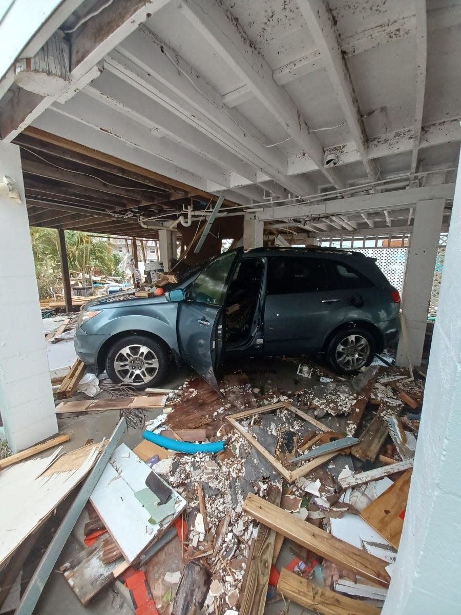 hurricane ian debris litters a car park with a car with an open door