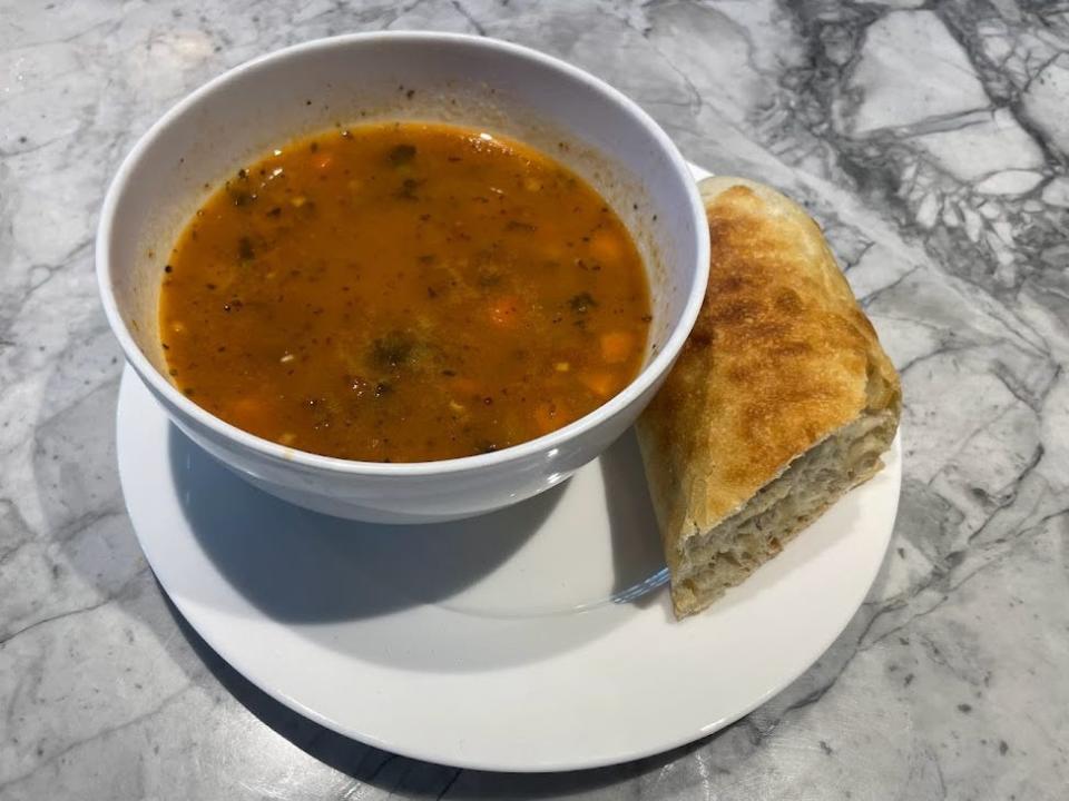 trader joe's hearty minestrone soup in a bowl with a piece of bread next to it