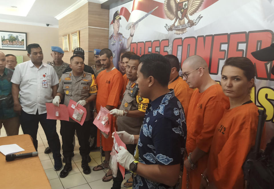 Police officers show evidence escort as they parade foreign nationals arrested for selling drugs during a press conference at the regional police headquarters in Denpasar, Bali, Indonesia, Friday, May 31, 2019. Police on the resort island have arrested an American, two Spaniards and two Russians for selling cocaine on the island. (AP Photo)