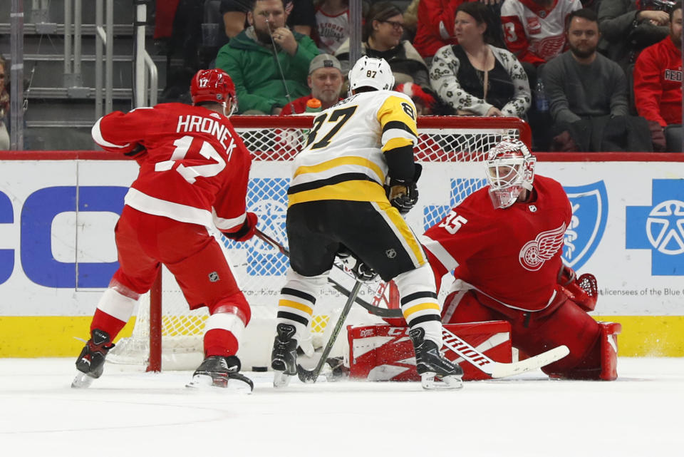 Pittsburgh Penguins center Sidney Crosby (87) scores the winning goal against Detroit Red Wings goaltender Jimmy Howard (35) as Filip Hronek (17) defends as in overtime of an NHL hockey game Friday, Jan. 17, 2020, in Detroit. (AP Photo/Paul Sancya)