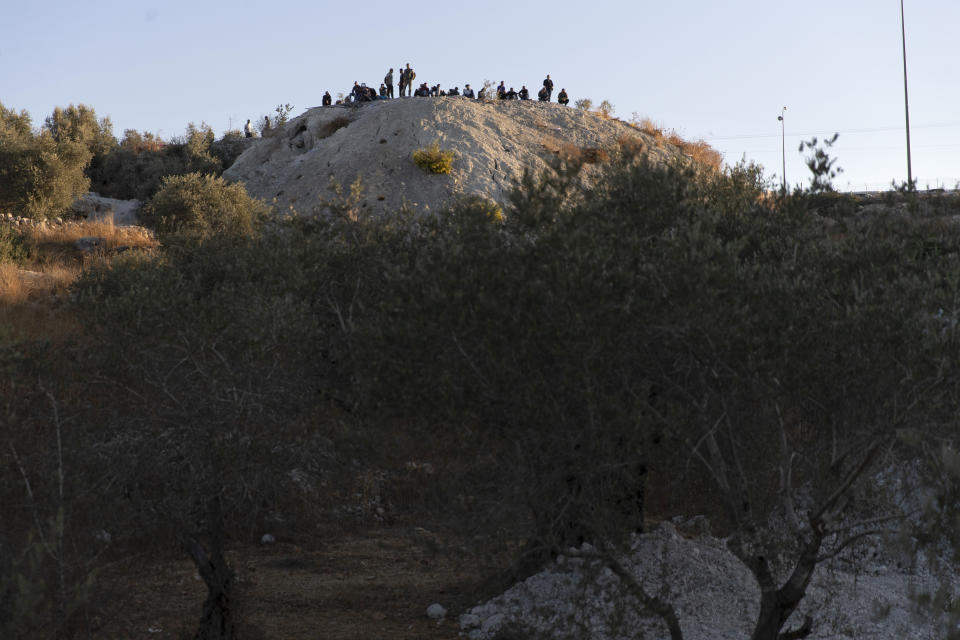 Palestinians gather on a hill overlooking a section of Israel's separation barrier, while they wait for the Israeli army to allow them to cross the fence, in the West Bank village of Nilin, west of Ramallah, Sunday, Nov. 7, 2021. Nearly two decades after Israel sparked controversy worldwide by building the barrier during a Palestinian uprising, it has become a seemingly permanent feature of the landscape — even as Israel encourages its citizens to settle on both sides. (AP Photo/Nasser Nasser)