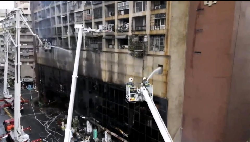 In this image taken from video by Taiwan's EBC, firefighters shoot water into a building that caught fire in Kaohsiung, in southern Taiwan on Thursday, Oct. 14, 2021. The fire engulfed a 13-story building overnight in southern Taiwan, the island's semi-official Central News Agency reported Thursday. (EBC via AP )