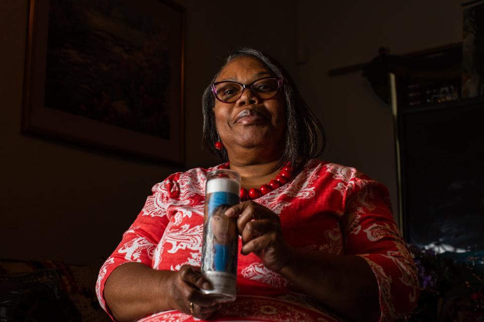 Joann McFadden holding a candle w/ a photo of Kenne