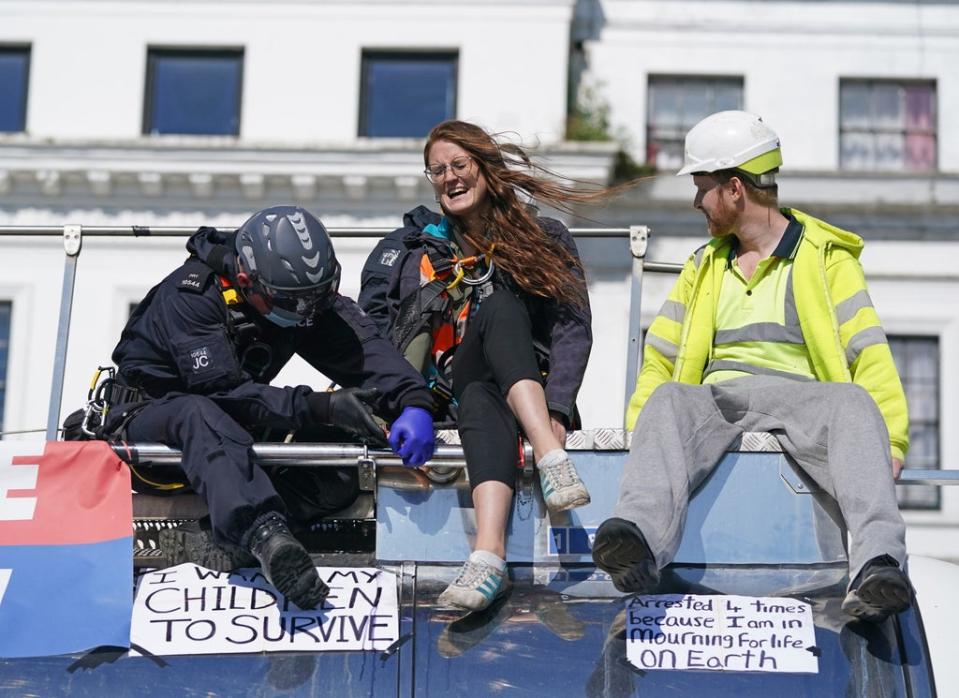 Police officers remove two protesters from the top of a tanker (PA)