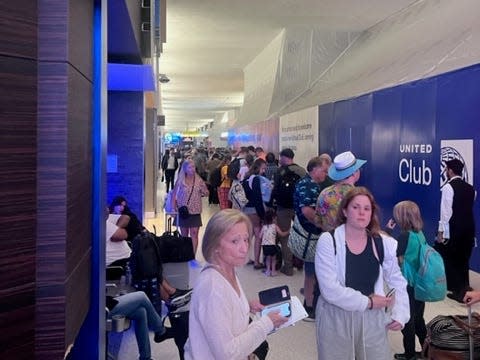 Passengers queuing at a United Airlines customer-service desk at an airport.