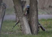 An Ukrainian soldier takes cover behind a tree as pro-Russia protesters gathered in front of a Ukrainian airbase in Kramatorsk, in eastern Ukraine April 15, 2014. Ukrainian armed forces on Tuesday launched a "special operation" against militiamen in the country's Russian speaking east, authorities said, recapturing a military airfield from pro-Moscow separatists. REUTERS/Marko Djurica (UKRAINE - Tags: POLITICS CIVIL UNREST MILITARY TPX IMAGES OF THE DAY)