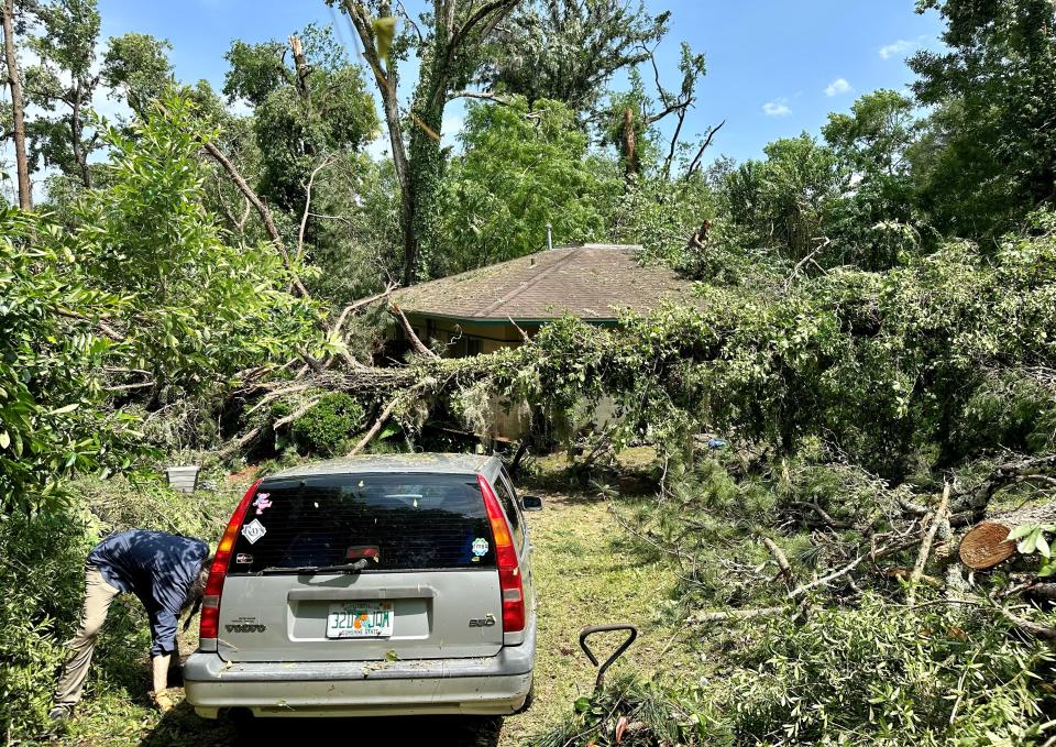 Kevin Sansom, left, and Laura Floyd, seen on the roof, clean up around their place on West Indianhead Drive. "This is quite a sight, isn't it?" Sansom asked. "It's going to take quite a while to clean this up."