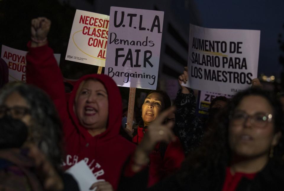 A crowd of people holding signs and chanting at night