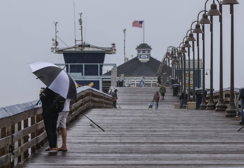Imperial Beach, CA - September 09: Despite high wind and rain, people enjoy the stormy weather during the morning hours on the Imperial Beach Pier on Friday, Sept. 9, 2022 in Imperial Beach, CA. (Eduardo Contreras / The San Diego Union-Tribune)